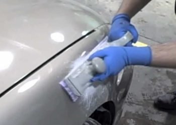 Technician performing auto fiberglass repair on a body panel